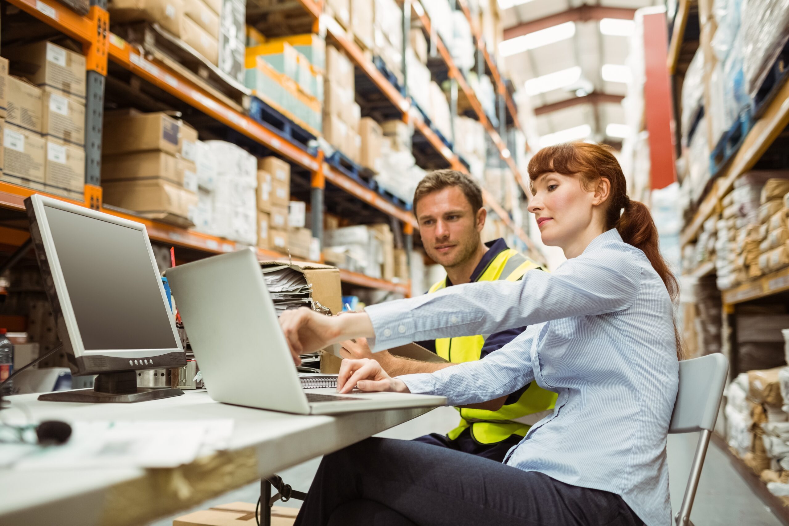 Warehouse worker and manager looking at laptop Warehouse worker and manager looking at laptop
